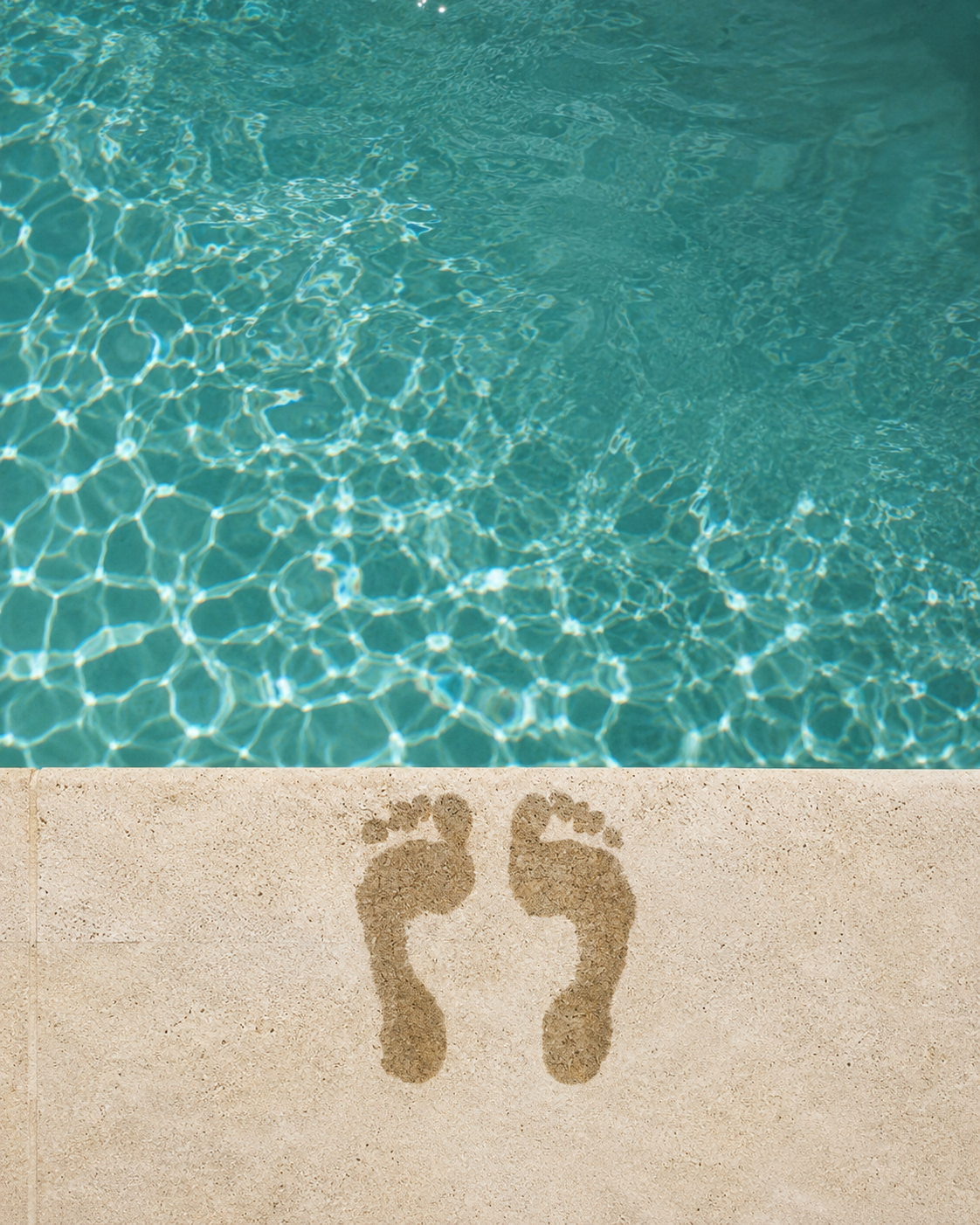 Blue pool full of water with marks of two wet feet